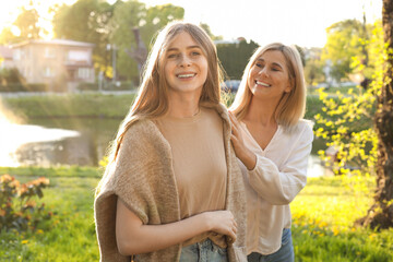 Wall Mural - Happy mother with her daughter spending time together in park on sunny day