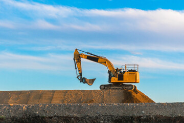 Large yellow heavy machinery excavator digger on a road construction site. Road works