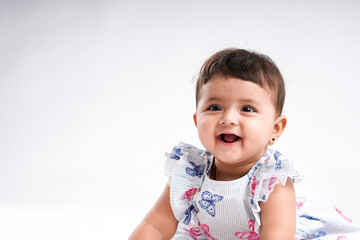 Indian baby girl sitting on white background.