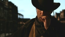 Portrait Of Cowboy Smoking A Cigar, Old Wild West City In The Background. Spaghetti, Macaroni Western Style Cinematic Footage
