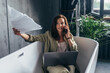 © undrey - Woman sits in the bathtub with her papers and calls