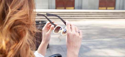 Wall Mural - Young woman holding sunglasses in outdoors.