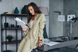 © undrey - Woman stands at desk and looks through documents.