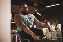 A Person In A Wheelchair Inside A Gym Training His Lats.