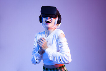 Happy Young woman in white sweatshirt wearing black vr headset watching playing and hand touching on the purple background. Metaverse concept.