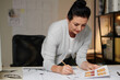 © DragonImages - Experienced architect double checking house floor plan on her desk