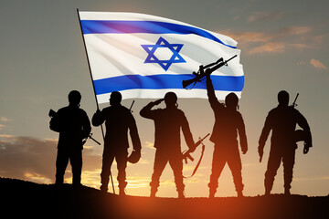 Silhouettes of soldiers with Israel flag against the sunrise in the desert. Concept - armed forces of Israel.