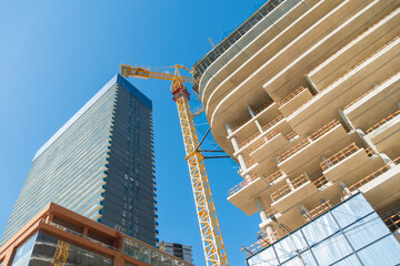 Wall Mural - View from below of new multi-storey buildings, a tower crane, multi-storey buildings under construction against the blue sky. Concept of development, urbanization, construction business
