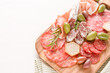 Traditional italian antipasti over white table. Wooden charcuterie board with different types of sausages - salami, bresaola, proscuitto served with olives. Menu background with copy space