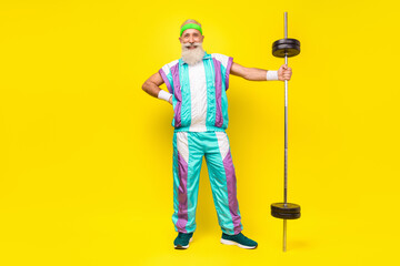 Poster - Full body photo of cheerful aged person put hand waist hold barbell isolated on yellow color background