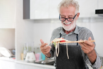 Man in kitchen. Old man cooking pasta. Happy retired senior man cooking in kitchen. Retirement, hobby people concept. caucasian senior cooking in kitchen.