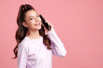 Wall Mural - Beautiful young asian women smiling with smartphone chatting with partners online on pink background,