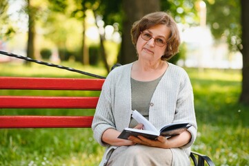 Poster - Retired woman reading a book on the bench