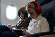 Children Are Flying On A Plane And Looking At A Tablet.