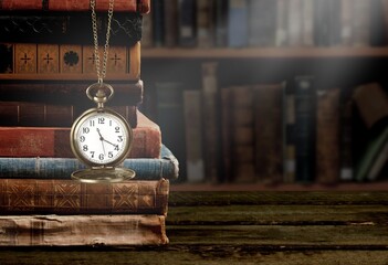 Wall Mural - old clock on a chain with stack books on library background. retro clock as a symbol of time a books