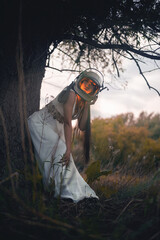 Young girl in the space helmet and white dress outdoors. Other planet journey concept.