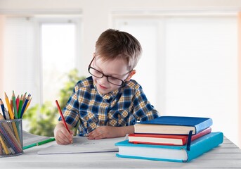 Smiling intelligent schooler teen doing homework, sitting at table, enjoying educational process