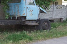 One Old Disassembled Truck With A Blue Cab Stands On The Street In Green Grass