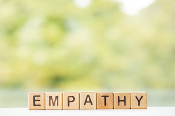 Empathy word is written on wooden cubes on a green summer background Closeup of wooden elements