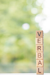 Verbal is written on wooden cubes on a green summer background Closeup of wooden elements