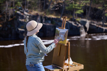 Girl artist paints nature on canvas with oil paints