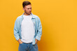 Pensive thoughtful tanned handsome man in blue basic t-shirt hold hands on pocket look aside posing isolated on yellow studio background. Copy space Banner Mockup. People emotions Lifestyle concept
