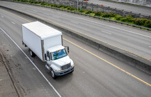 Powerful Compact Meddle Size Rig Semi Truck With Box Trailer Driving On The Highway Road With Exit Intersection