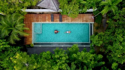 Wall Mural - couple men and woman in swimming pool in the jungle of Krabi Thailand, aerial view with drone above swimming pool in jungle of Thailand. 