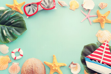 Wall Mural - nautical concept with tropical leaf, beach hat, seashells and starfish over mint blue wooden background
