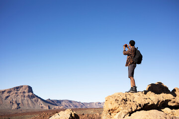 Young man taking pictures on a road trip. Man making memories on the mountain.