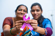 © WESTOCK - Doctor and patient showing breast cancer symbol by looking at camera - concept of healthcare, cure and awareness