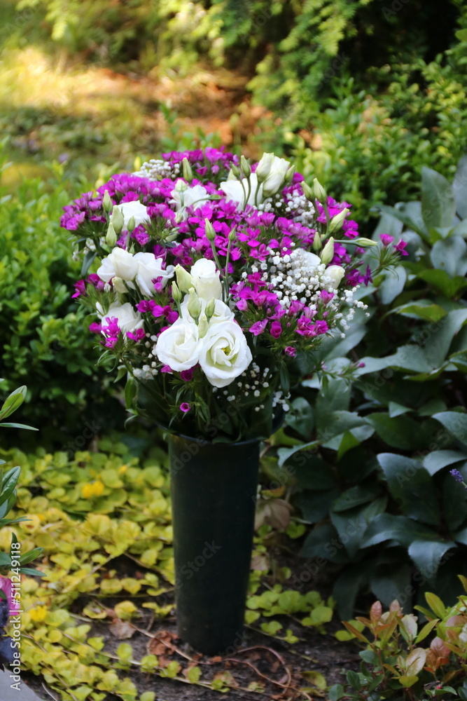 Stock-Foto „Bunter Blumenstrauss schmückt ein Grab im Sommer auf dem Friedhof“