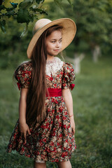 Wall Mural - Beautiful girl in a vintage dress 7-8 years old posing in the garden. Beautiful spring garden. The concept of a happy childhood, peace and happiness.