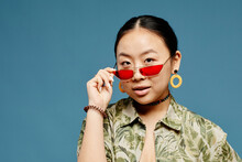 Minimal Portrait Of Asian Teenage Girl Wearing Trendy Colored Sunglasses Over Blue Background, Copy Space