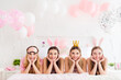 © deagreez - Portrait of four adorable girls hands touch cheeks laying white sheets bed house indoors