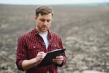 farmer standing in a plowed field. Agriculture, crop concept.