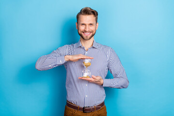 Poster - Photo of handsome man hold sanglass timer countdown till big sales on black friday isolated on blue color background