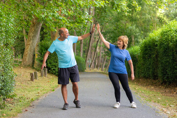 Man and woman giving five to each other after having finished an exercise well in an urban park