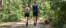 Back View Of Sports Couple Jog On Path In Forest