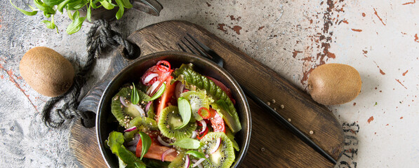 Wall Mural - bowl of salad with kiwi, tomatoes and chili peppers on the table