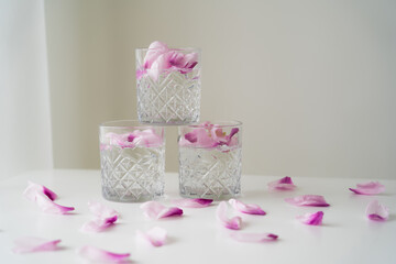 Sticker - crystal glasses with tonic and floral petals on white surface and grey background.