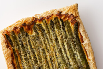 Baked puff pastry pie with cheese and asparagus on a white background, top view, copy space