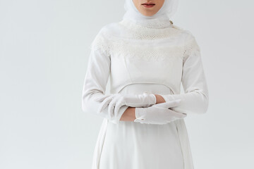 Wall Mural - cropped view of young muslim bride in gloves and white dress isolated on grey.
