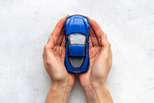 Toy Car In Hands, Top View. Car Insurance Or Driving Safety Concept