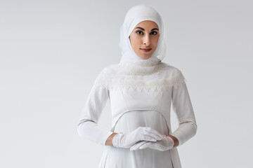 Wall Mural - pretty muslim bride in gloves and wedding dress isolated on grey.