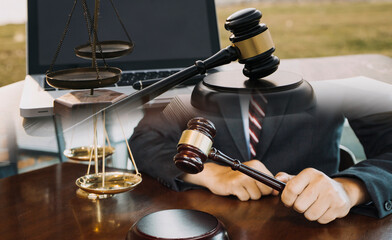 Justice and law concept.Male judge in a courtroom with the gavel, working with, computer and docking keyboard, eyeglasses, on table in morning light