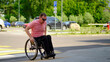 © Alex - Caucasian man in a wheelchair drives onto the sidewalk