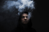 Fototapeta  - Dark portrait of a short haired girl wearing hoodie with smoke coming out of it. .