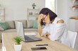 Woman has a burnout. Stressed tired female entrepreneur or remote worker sitting hand on head at work desk with laptop computer in home office, suffering from headache, feeling down, upset, frustrated