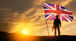 Silhouette of soldier with United Kingdom flag on background of sunset. Greeting card for Poppy Day, Remembrance Day. United Kingdom celebration.